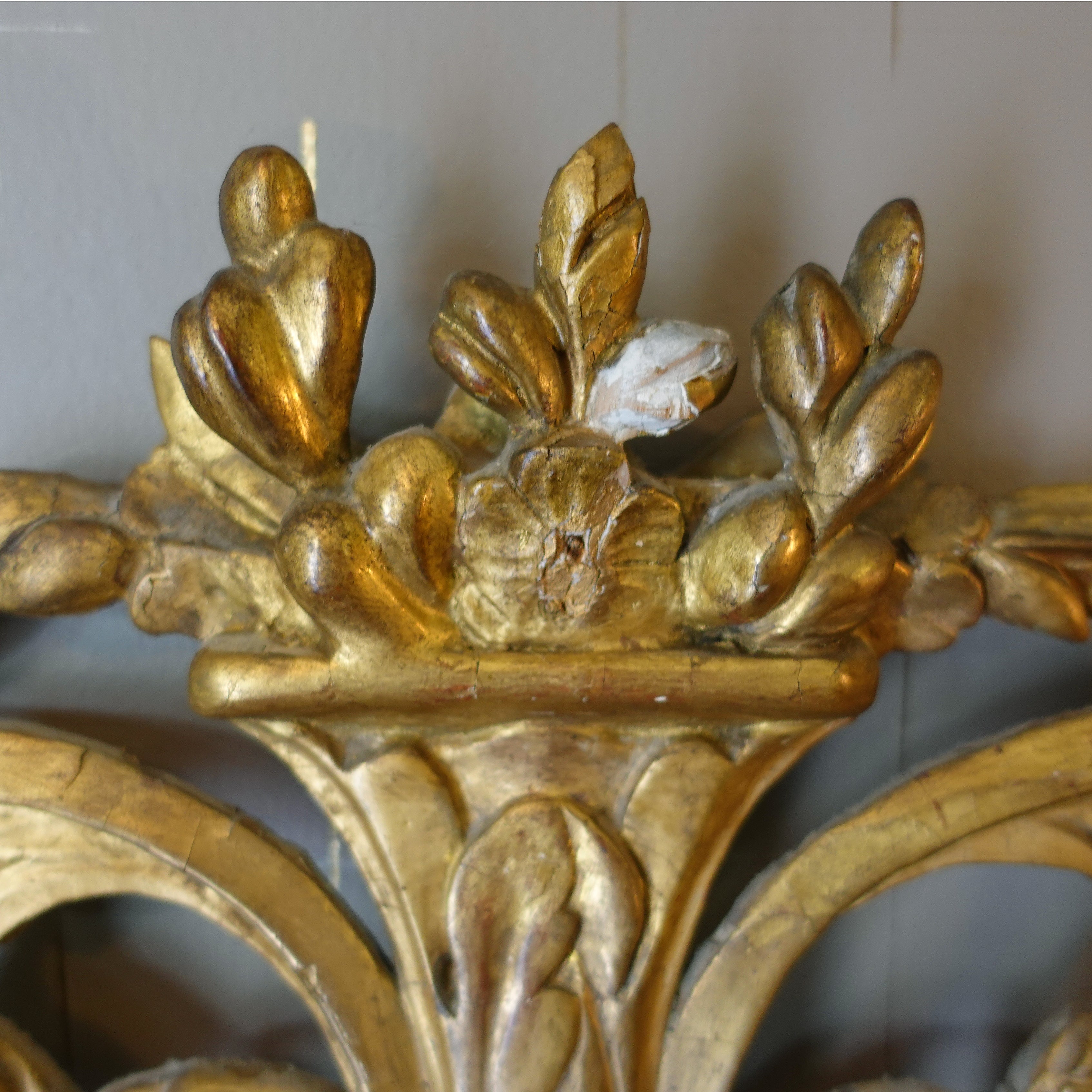 Close-up of an ornate gold mirror with intricate designs.