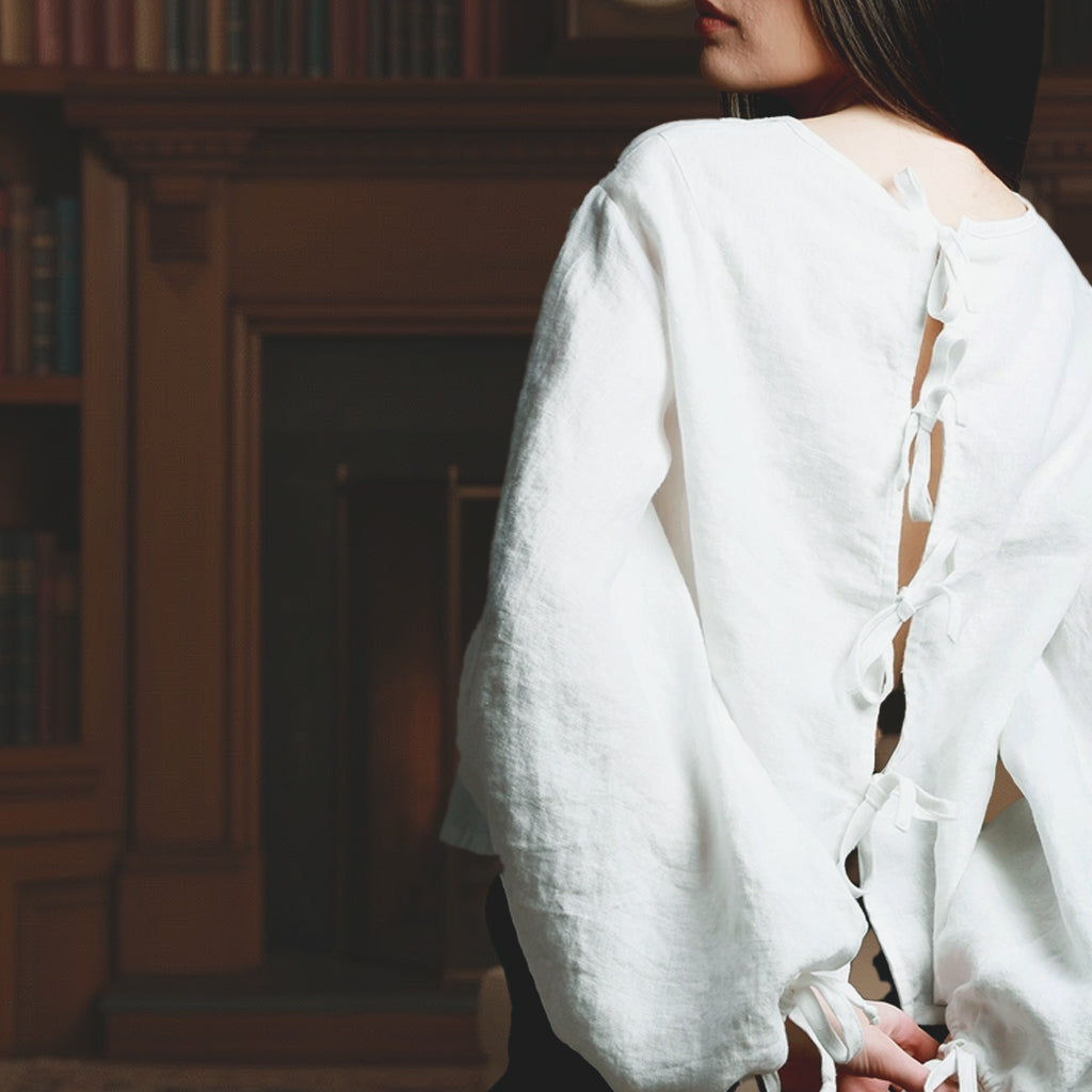 Elegant open back design of a white linen shirt featuring delicate back tie closures and heritage French seams.