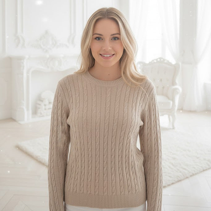 Woman wearing a beige sweater in a bright, white room.