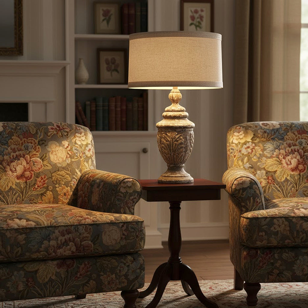 Provence Home Antique Finial style handcarved wooden distressed Table Lamp on a small table between two floral armchairs in a living room.