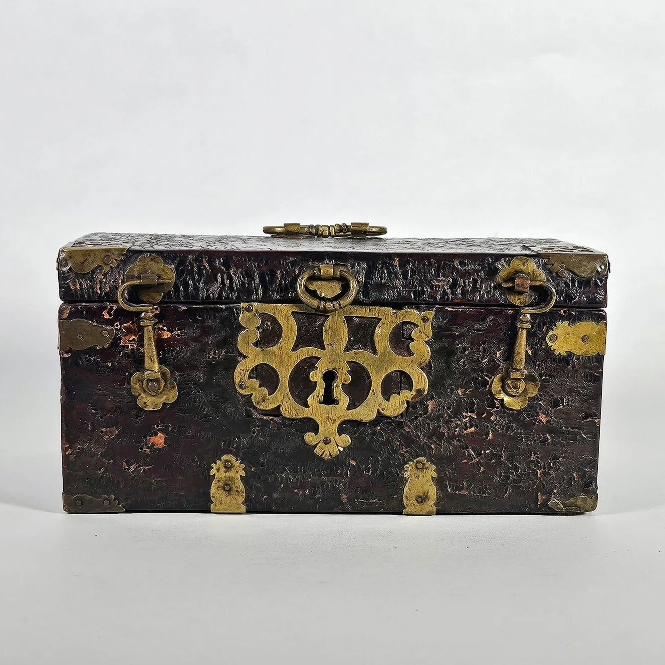 Antique leather chest with brass openwork escutcheon and hardware front view Le Historique