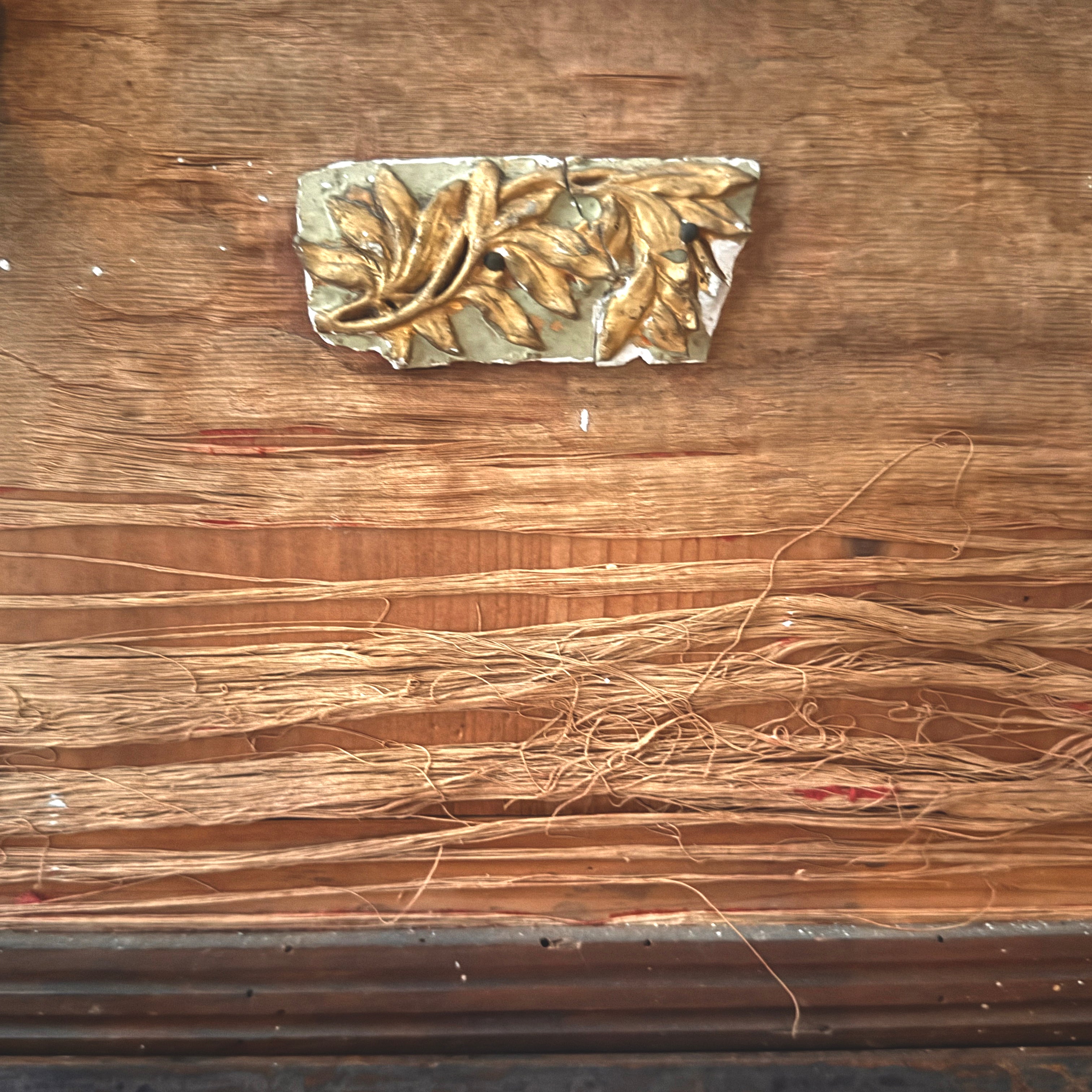 Decorative metal leaf design on a wooden surface with raw silk