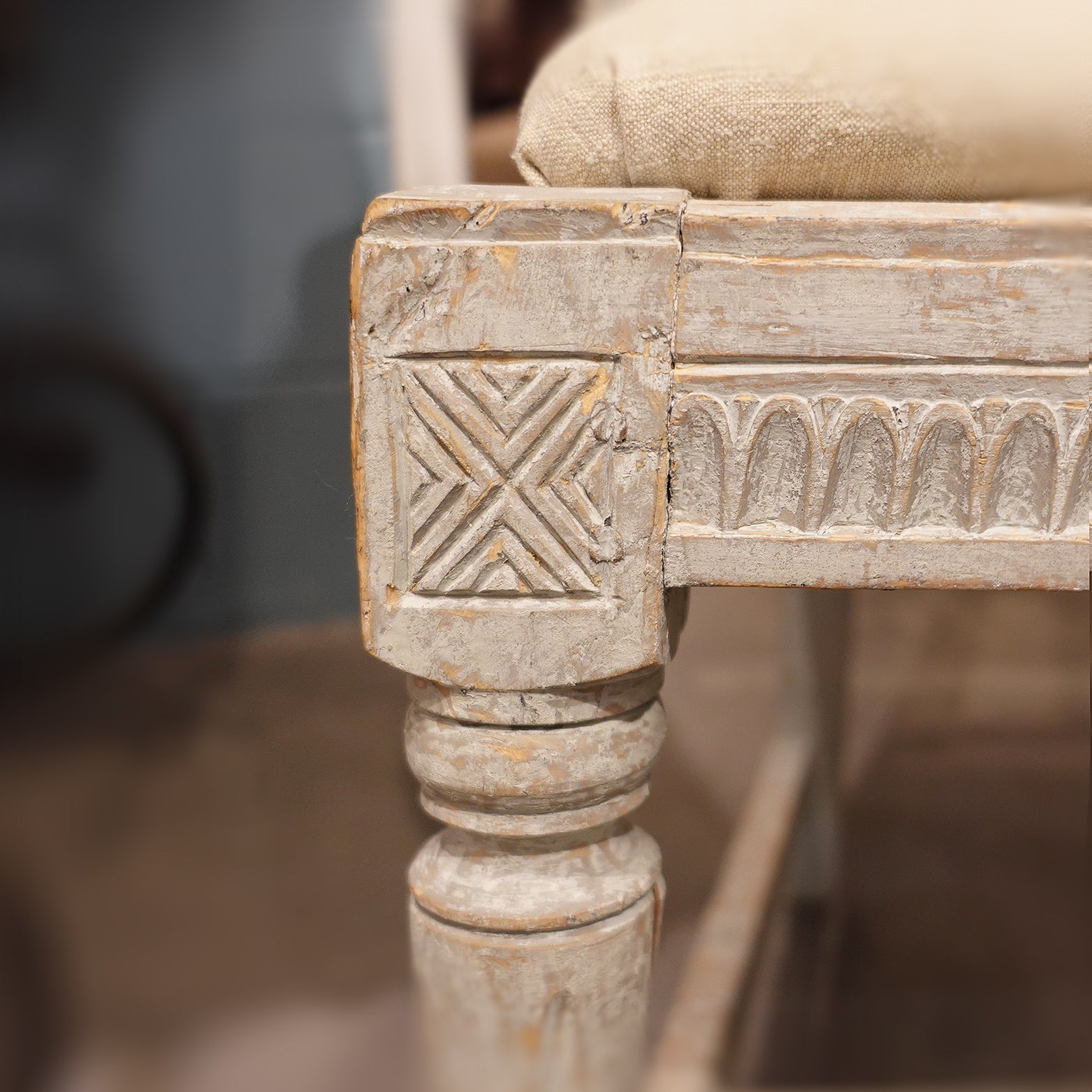 Detail of an Antique Swedish Gustavian hand-carved time worn accent chair in neutral tones with a linen cushion.