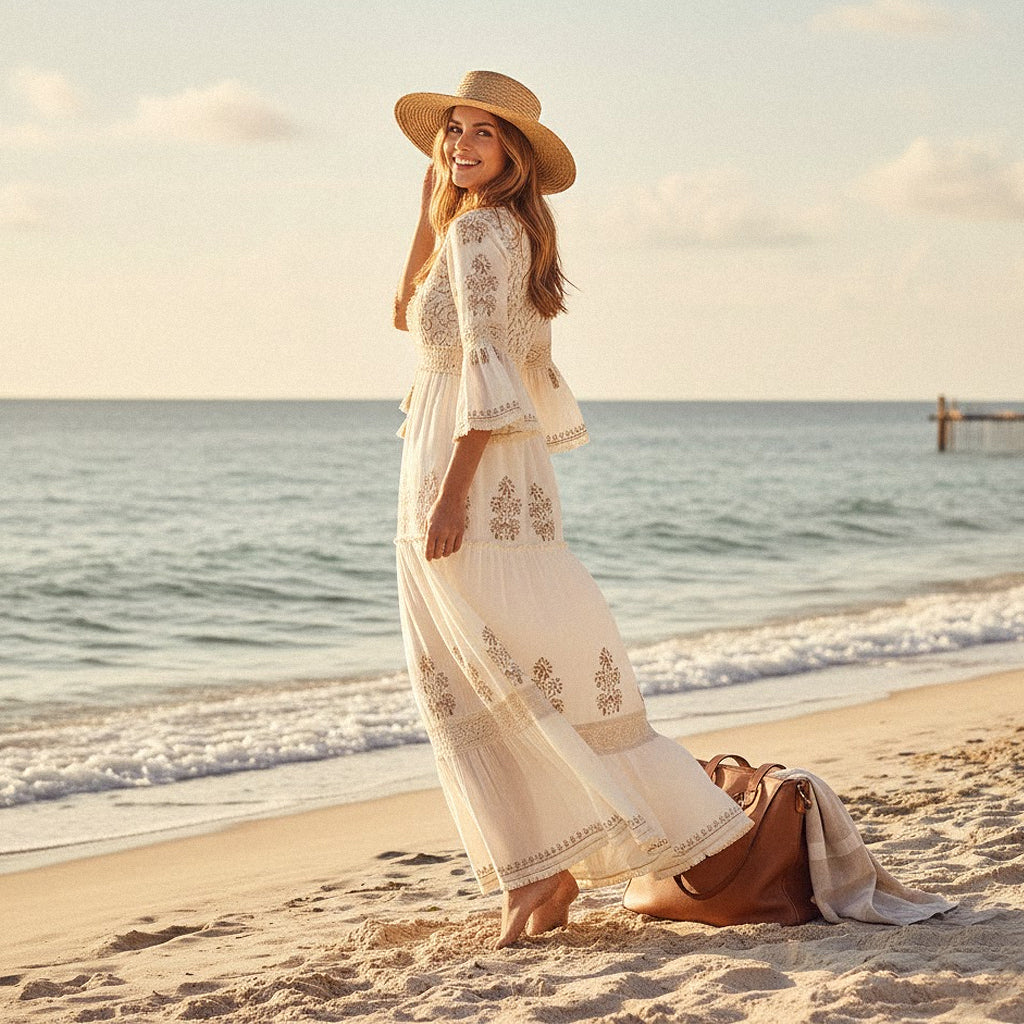 A smiling model wearing a bohemian floral maxi dress with lace trim and embroidery on a sun-drenched beach, embodying a romantic, high-end preppy summer aesthetic.