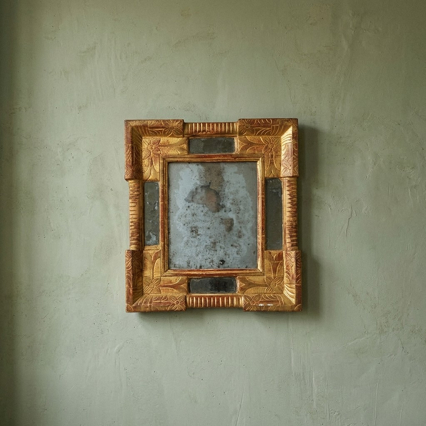 Authentic 17th-century Italian Baroque giltwood cassetta mirror featuring hand-carved floral motifs, red bole patina, and heavily oxidized mercury glass from Le Historique.