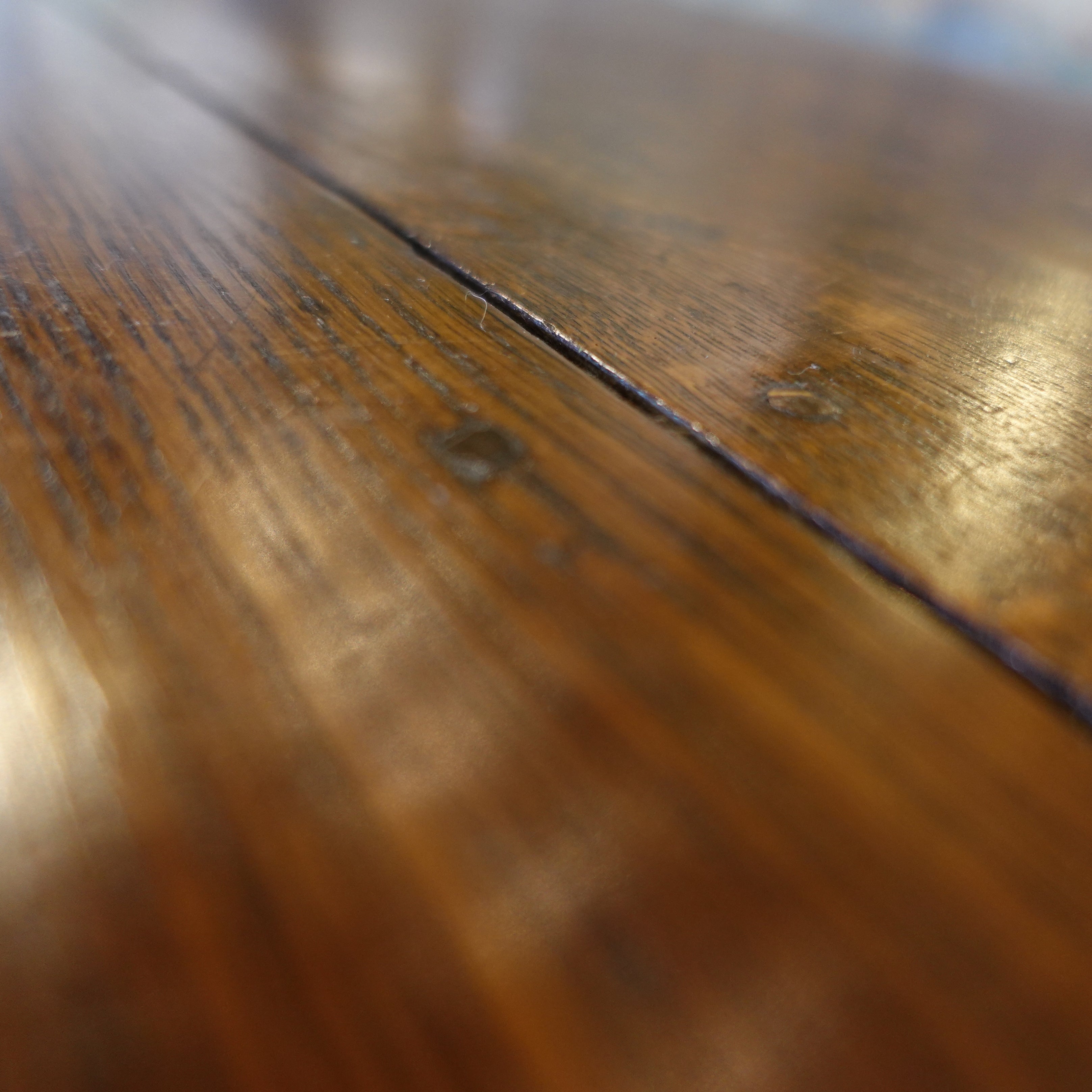 Close-up of a wooden surface with visible grain and texture on an Antique early 1800s English oak drop-leaf gateleg table