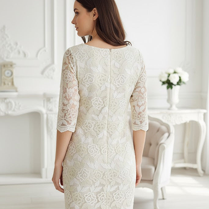 Woman wearing a white lace dress in a bright, elegant room.