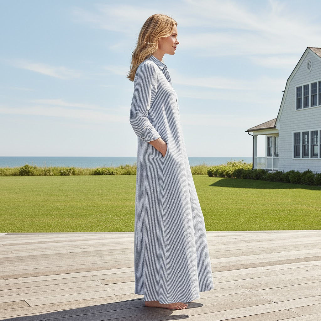 Side profile of a woman in a long-sleeved navy striped linen dress highlighting the elegant silhouette and heritage craftsmanship.