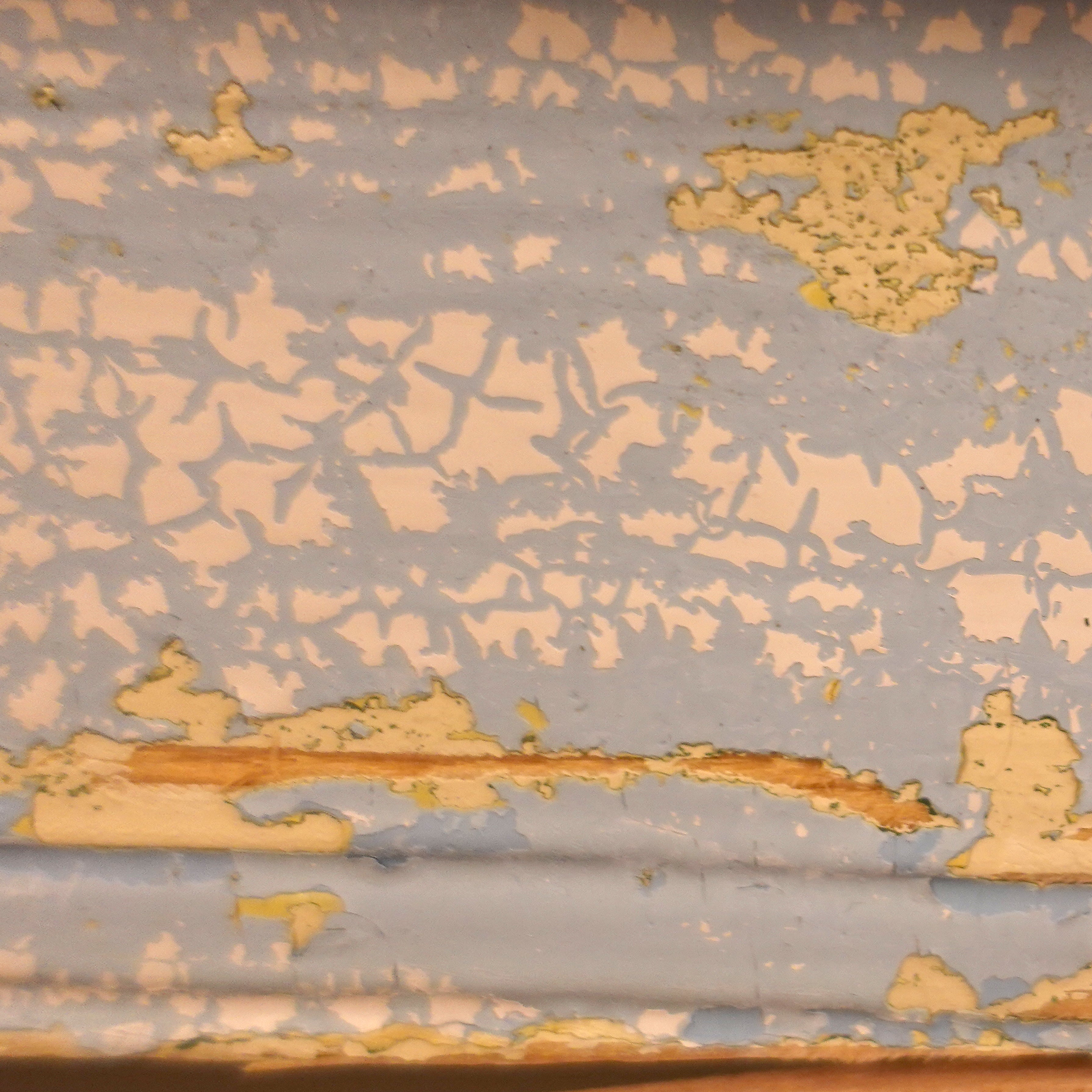 Extreme close-up of original Gustavian paint layers in pale blue and cream, demonstrating the authentic aged texture and antique character of heritage furniture.