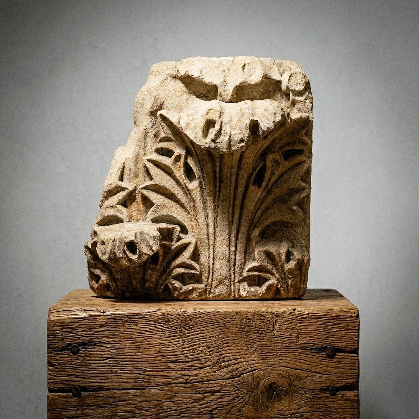Decorative stone architectural element on a wooden block against a gray background