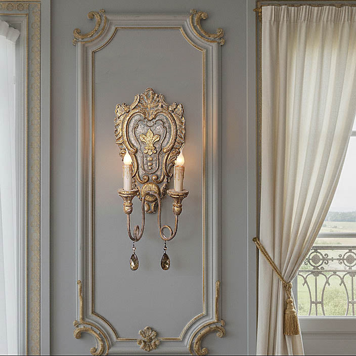 Decorative wall sconce with intricate design on a gray wall next to a window with white curtains.